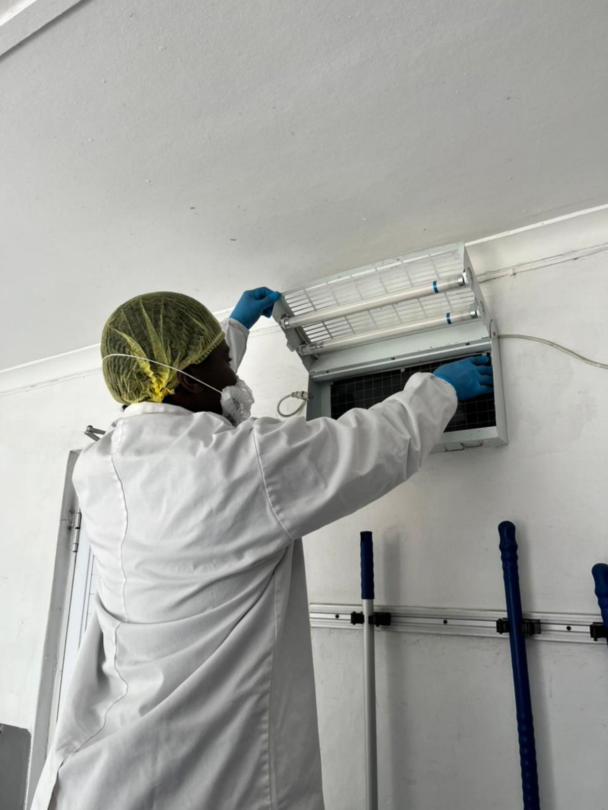 ASC Pest Control technician servicing an insect light trap in a food facility